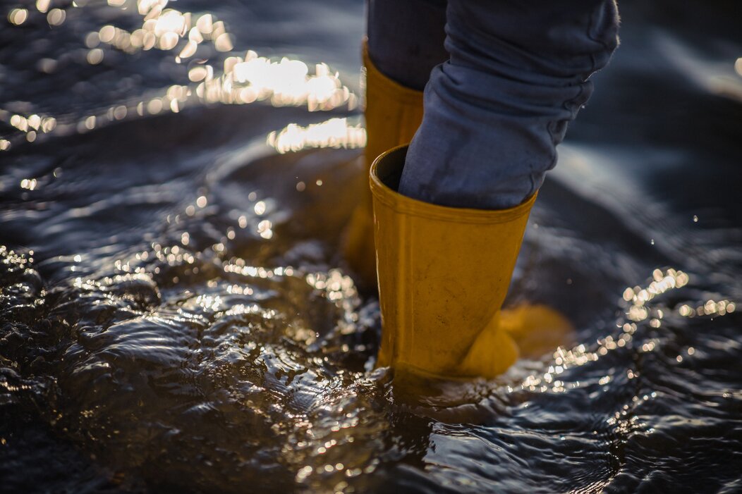 Photo d'une personne marchant dans l'eau avec des bottes jaunes